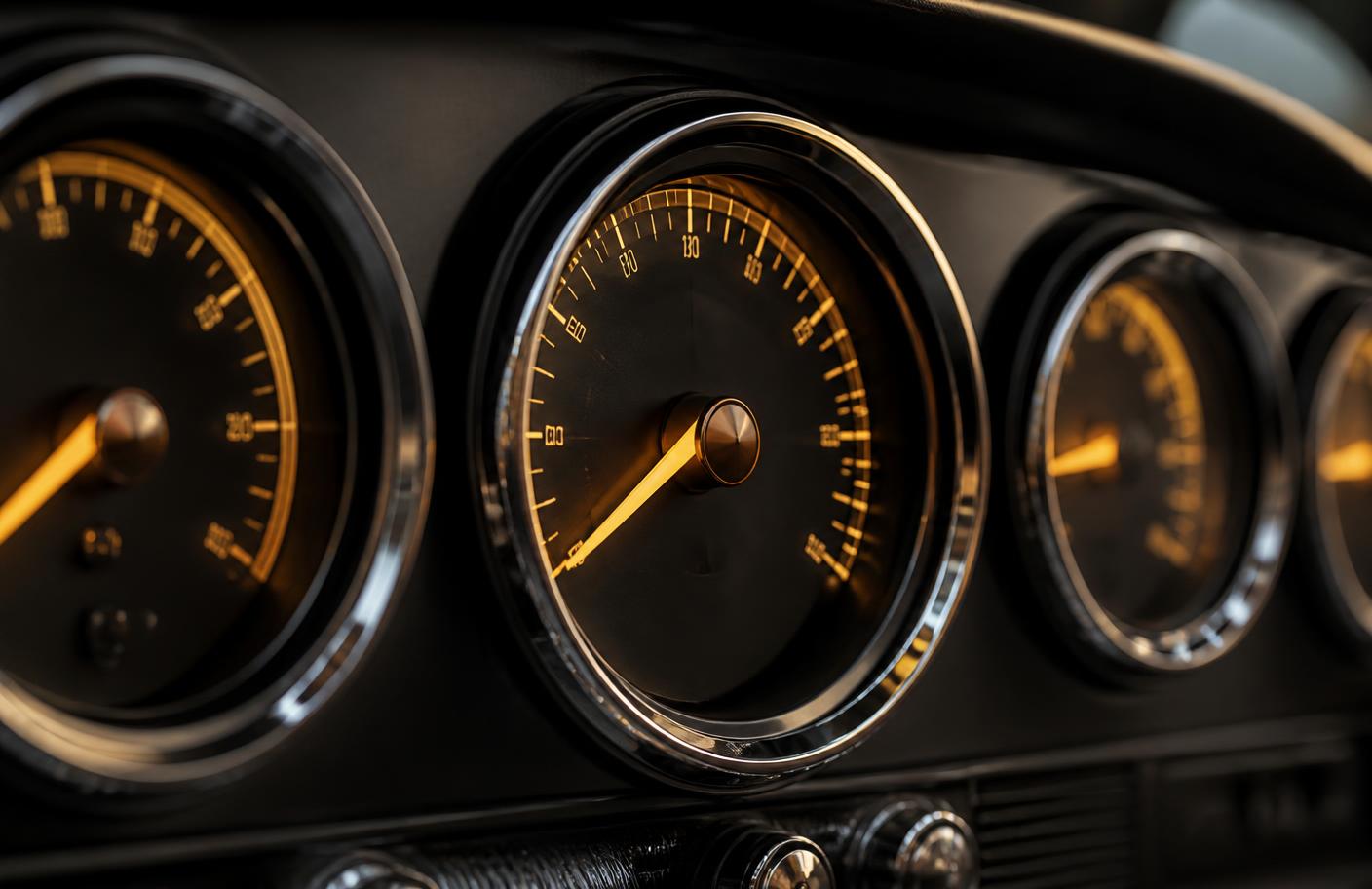 Close-up of a classic car instrument cluster with amber-lit gauges